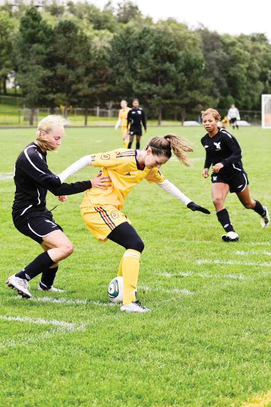 Gaels' winger Riley Filion holds off a Carleton Ravens defender during her team's 2-0 win on Saturday.
