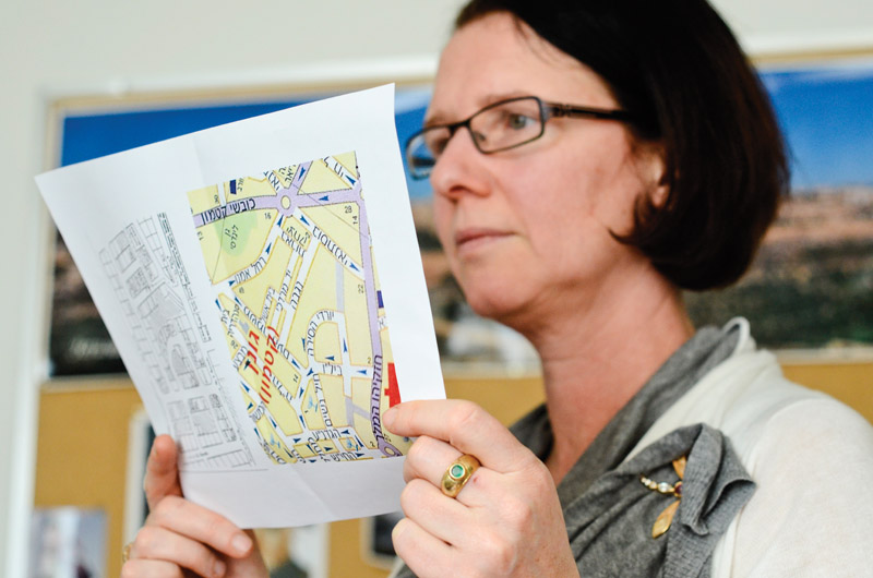 Queen's professor of film and media Dorit Naaman holds up two maps of Qatamon