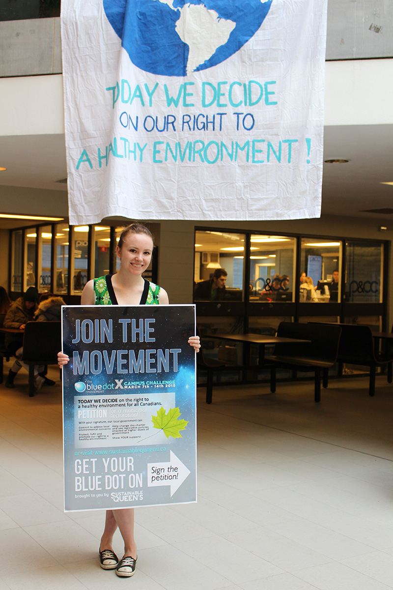 Leah Kelley holding a Blue Dot poster in the JDUC.