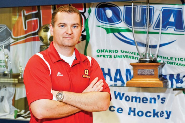 Women’s hockey coach Matthew Holmberg poses with the OUA women's hockey championship trophy.
