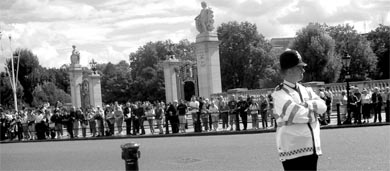 A London police officer stands guard while hundreds of tourists line the streets of Buckingham Palace and watch the Changing of the Guard.