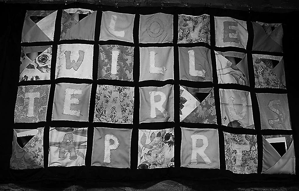 A quilt with brightly-coloured patches of material spelling out “Love will tear us apart” is part of Lisa Visser’s exhibit by the same name currently on display at the Sleepless Goat Café.