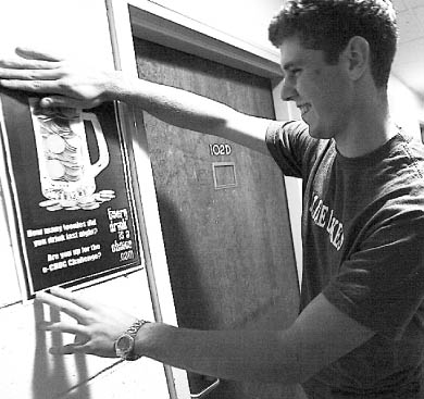Residence Life coordinator Matthew Brown puts up signs in Victoria Hall reminding students to think before they drink.