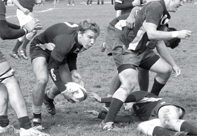 A Queen’s men’s rugby player hands off the ball during Saturday’s final regular season match.