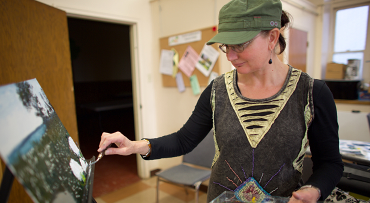 Paula Formanek working on her painting of a garden near the waterfront.