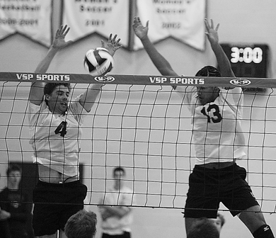 Queen’s setter Devon Miller (4) makes a block Friday as teammate Michael Amoroso looks on.