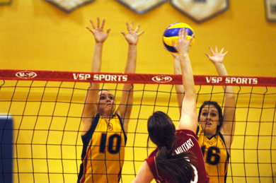 RMC’s Rebecca Fielding goes for a kill Wednesday against Queen’s Becky Billings (10) and Leah Franco (16). The Gaels beat the Paladins in straight sets.