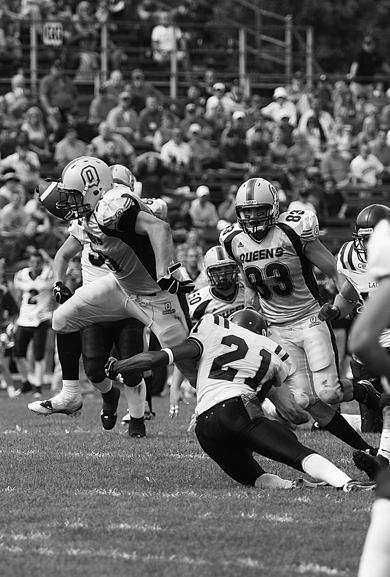 Queen’s running back Mike Giffin hurdles Laurier free safety Courtney Stephen Saturday as teammate Scott Stinson (83) looks on. The Gaels beat Laurier for the first time in five years.