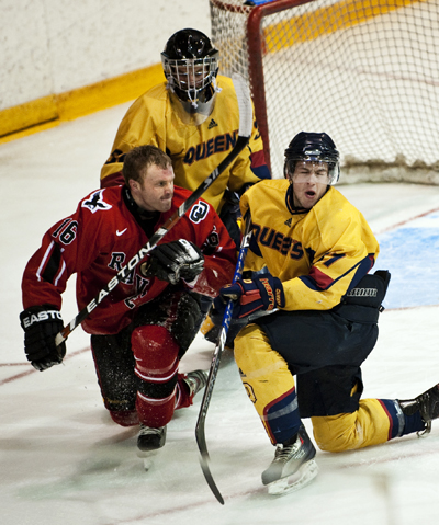 Queen's forward Brock Ouellet knocks Ravens' forward Chris Downey's helmet off during the Gaels' 4-1 loss at the Memorial Centre on Friday night. The Gaels take the ice on Sunday for the deciding game of the best-of-three series.