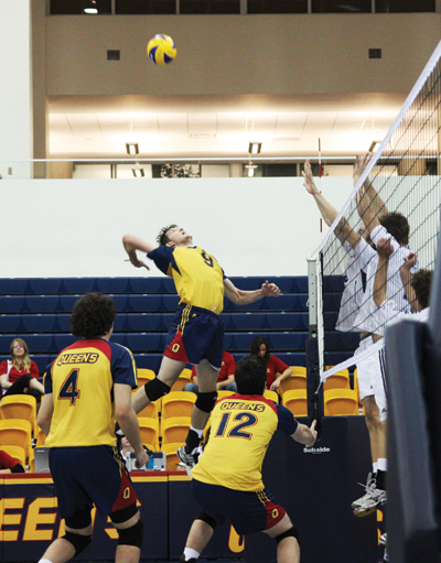 Outside Bryan Fautley jumps up for the spike as his teammates watch on.